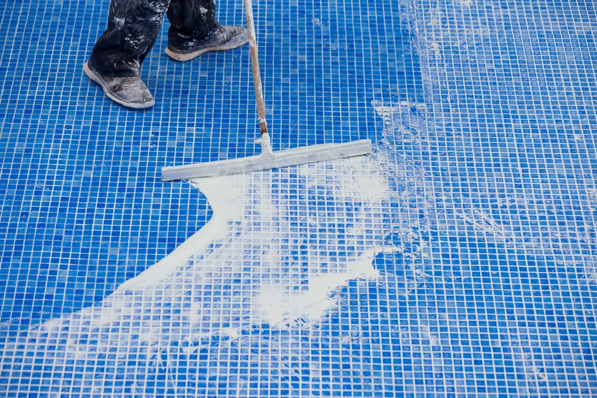 Una persona está limpiando una piscina con una escoba.