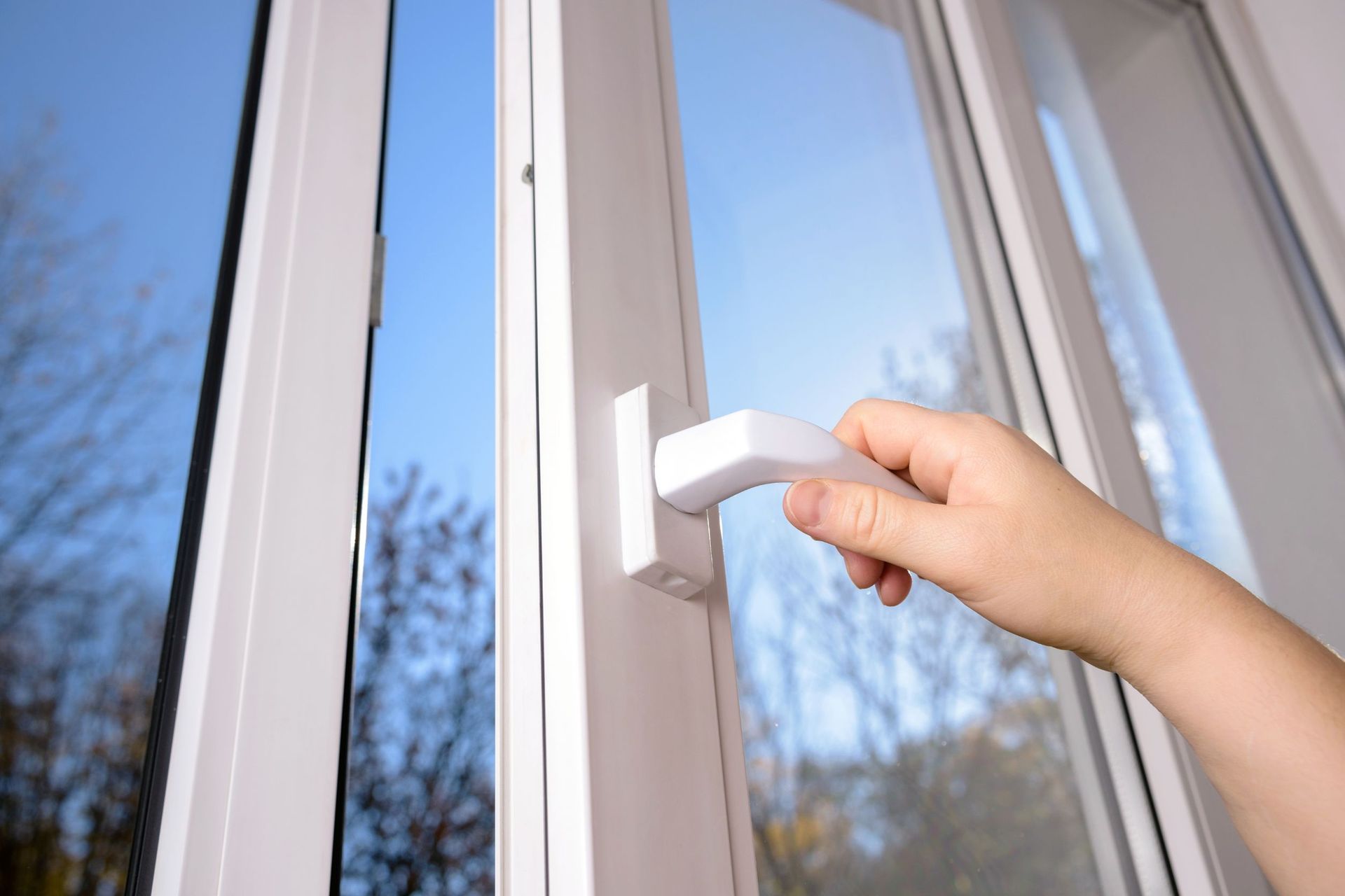 Una persona está abriendo una ventana con una manija blanca.