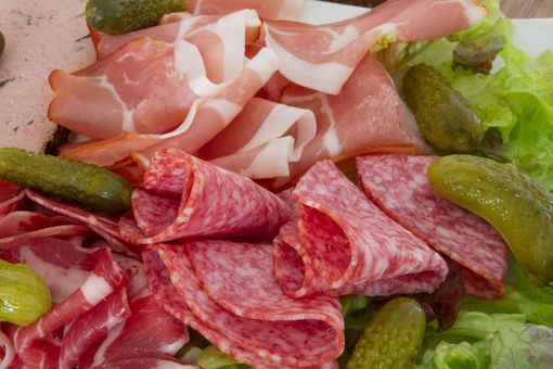 Assortiment de charcuteries, de cornichons et de laitue sur un plateau.