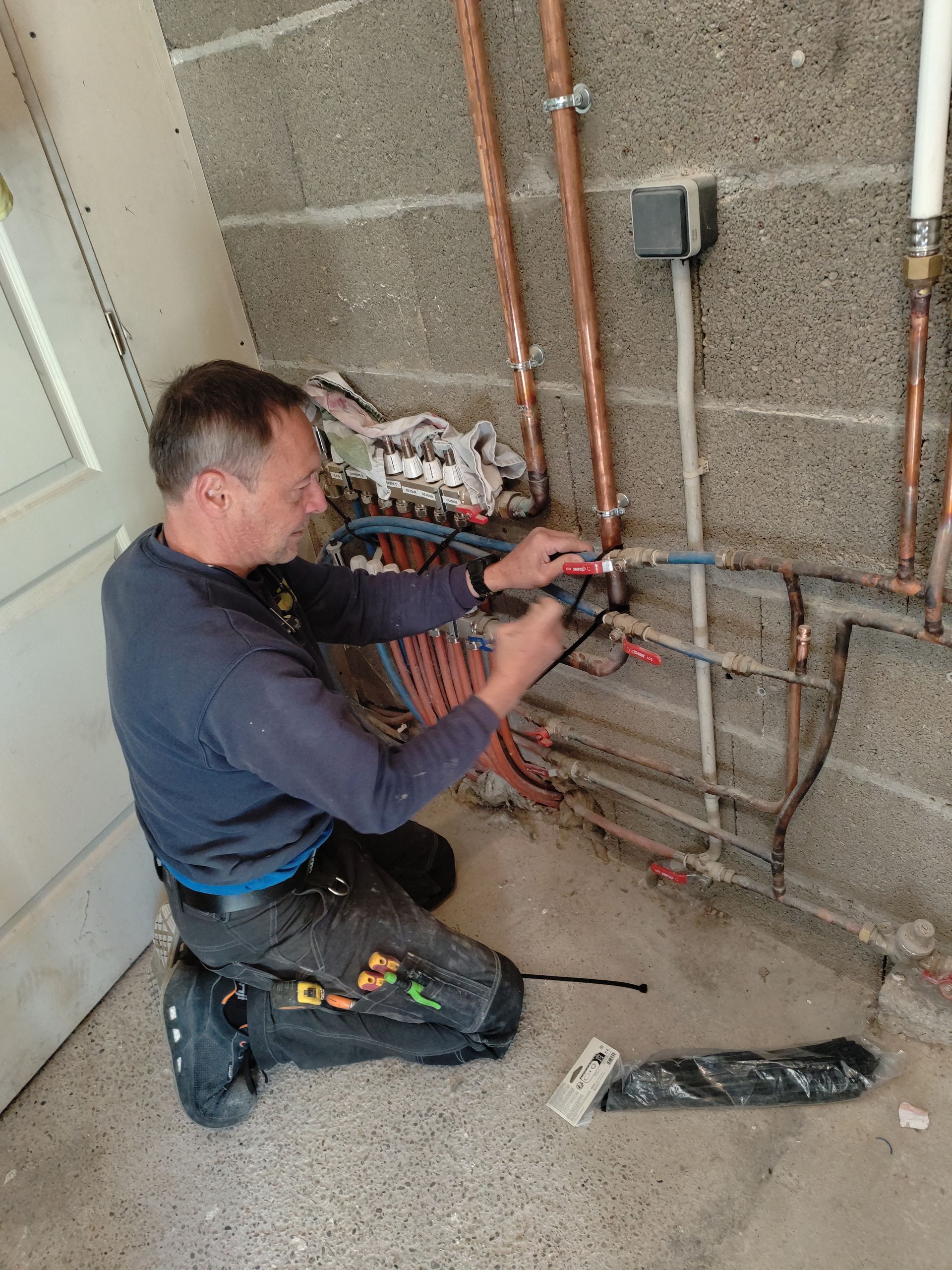 Un plombier à genoux.