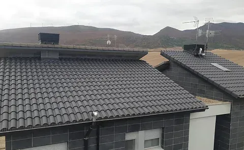 Una casa con techo de tejas y montañas al fondo.