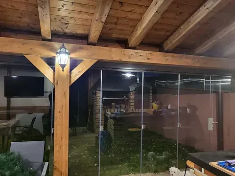 Un patio con puertas corredizas de vidrio y techo de madera por la noche.