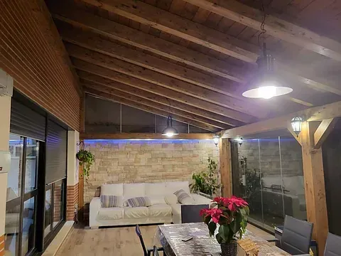 Una sala de estar con sofá, mesa y sillas bajo un techo de madera.