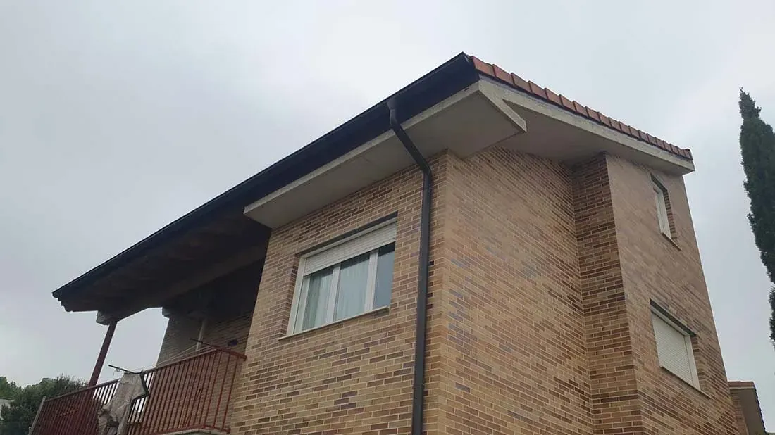 Una casa de ladrillo con techo negro y balcón.