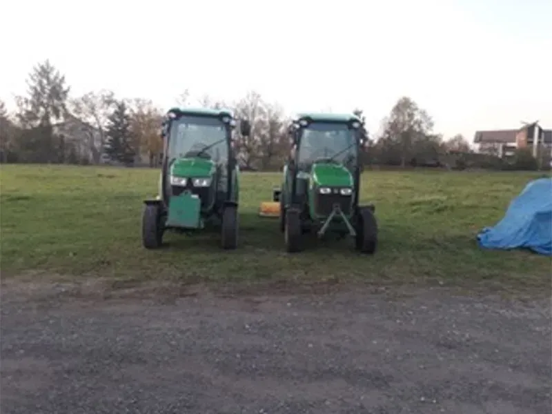 Zwei grüne Traktoren stehen nebeneinander auf einer Wiese. Gala Bau & Service GbR