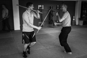 zwei Männer üben Kali mit Stöcken
