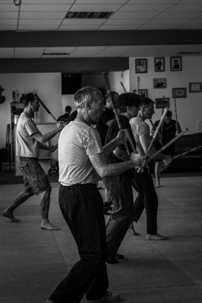 mehrere Personen trainieren Kampfposen mit Stöcken