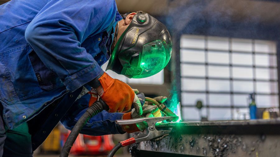 Ein Mann schweißt in einer Fabrik ein Stück Metall.