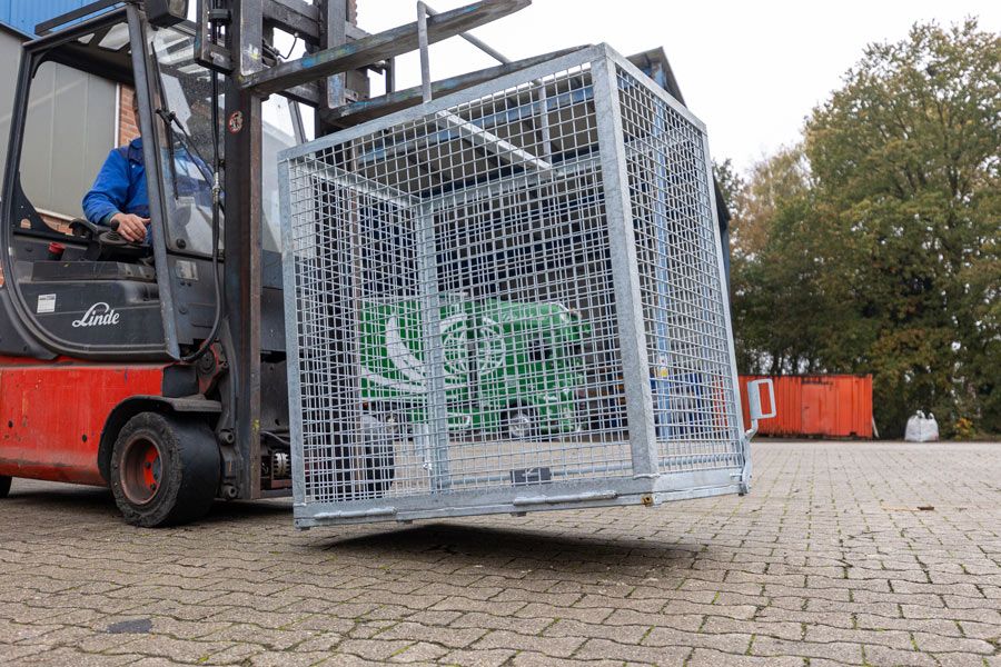 Ein Gabelstapler transportiert einen Metallkäfig über eine Ziegelsteinstraße.
