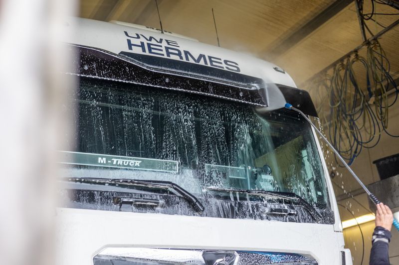 Ein weißer LKW wird mit einem Hochdruckreiniger gereinigt.