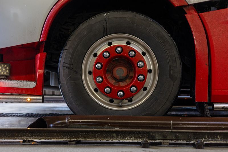 Ein roter Lastwagen steht auf einer Hebebühne in einer Garage.