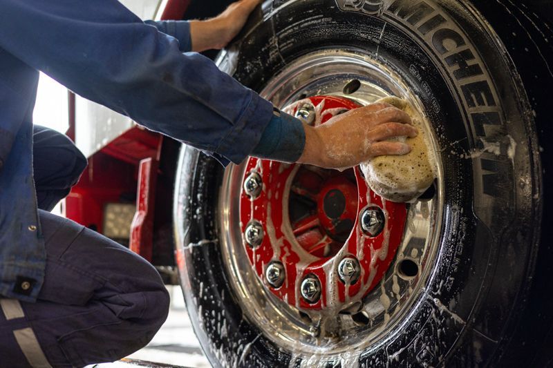 Ein Mann reinigt einen Reifen mit einem Schwamm.