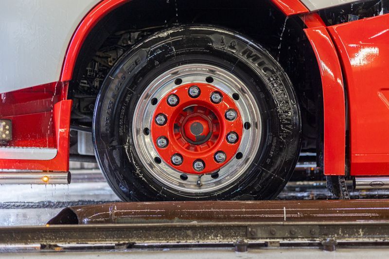 Ein roter LKW mit roter Felge steht auf einer Hebebühne.