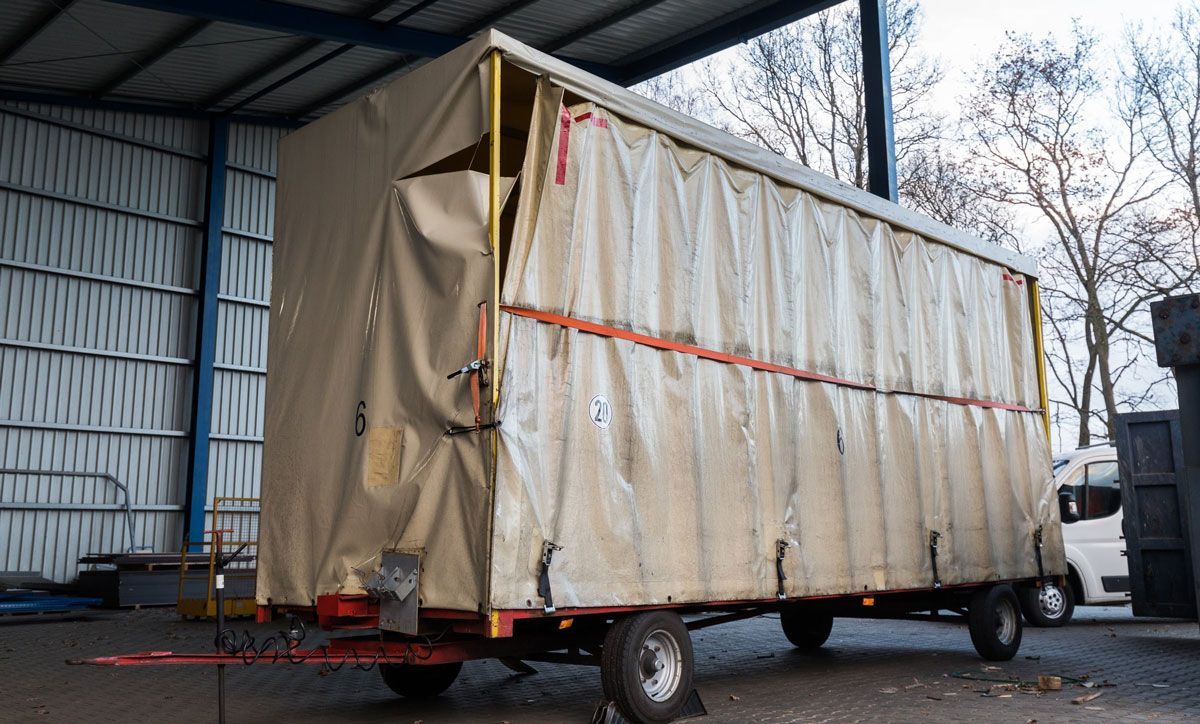 Ein mit einer Plane bedeckter LKW ist unter einem Dach geparkt.
