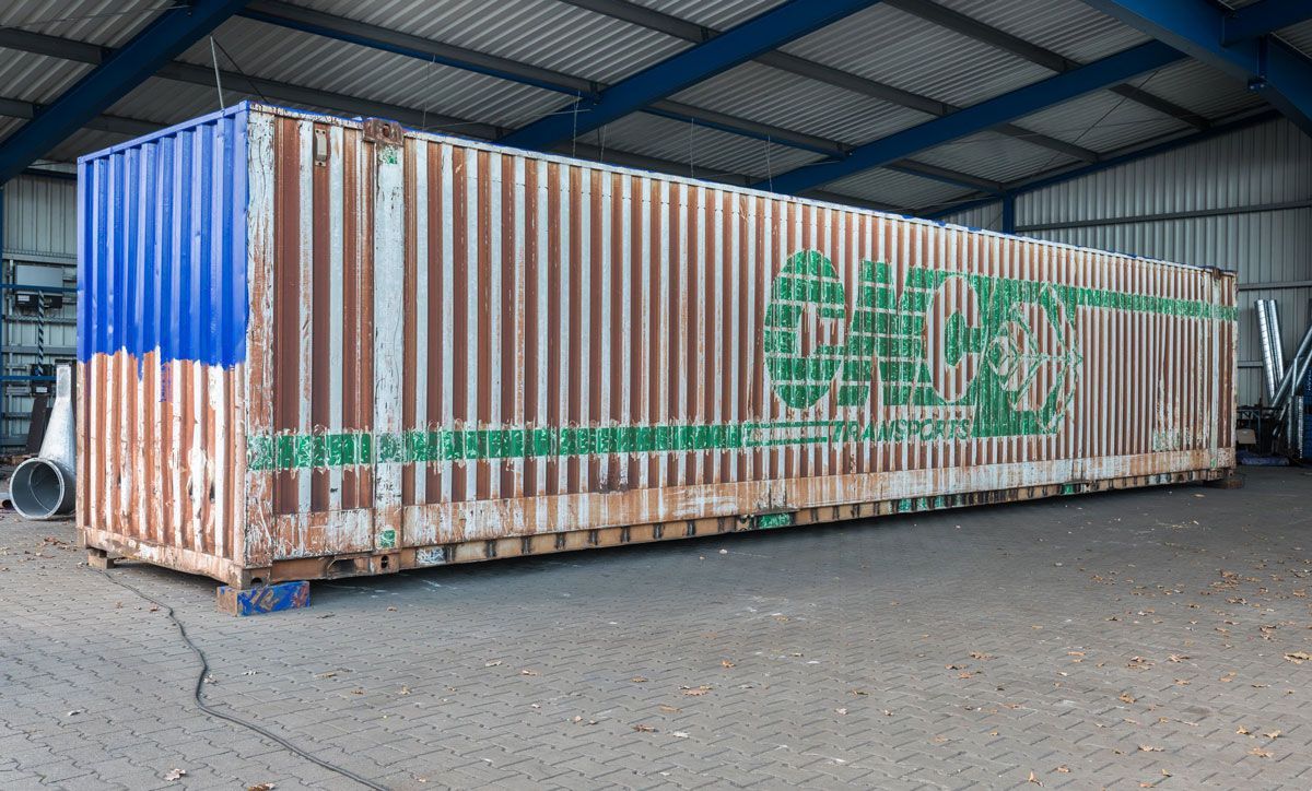 Ein großer rostiger Frachtcontainer steht in einem Lagerhaus.