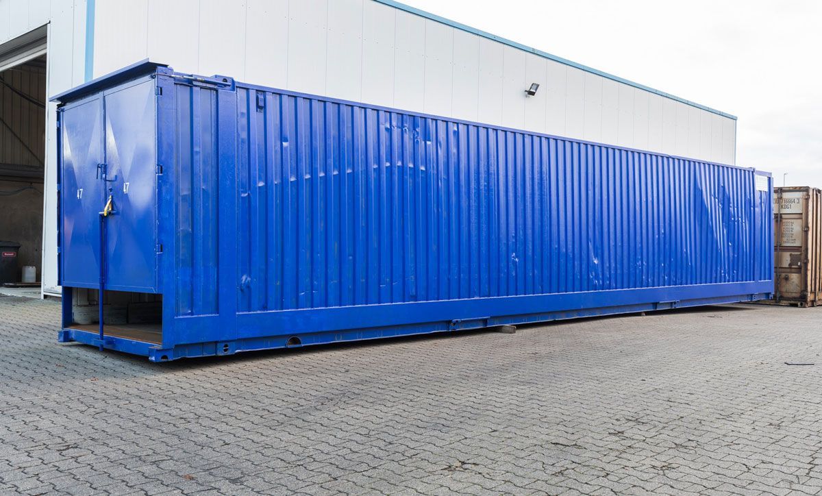 Ein großer blauer Frachtcontainer steht vor einem Gebäude.