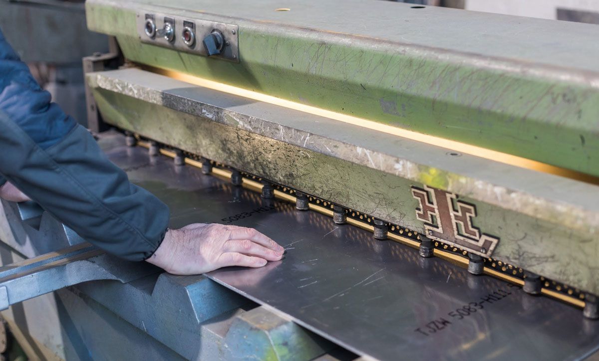 Eine Person verwendet eine Maschine, um ein Stück Metall zu schneiden.
