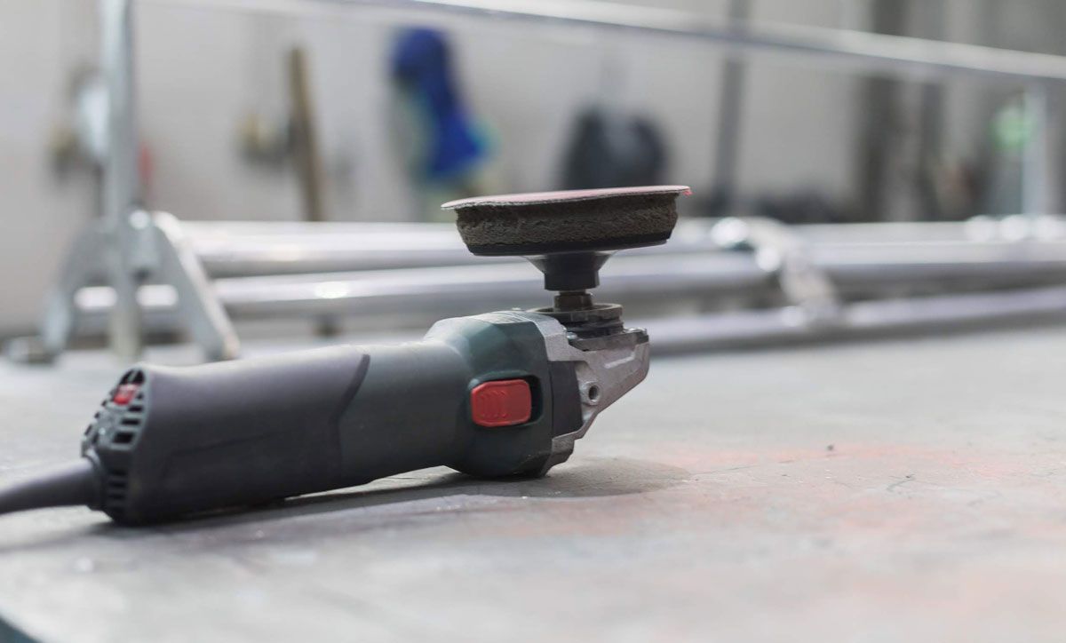 In einer Werkstatt steht eine Schleifmaschine auf einem Tisch.