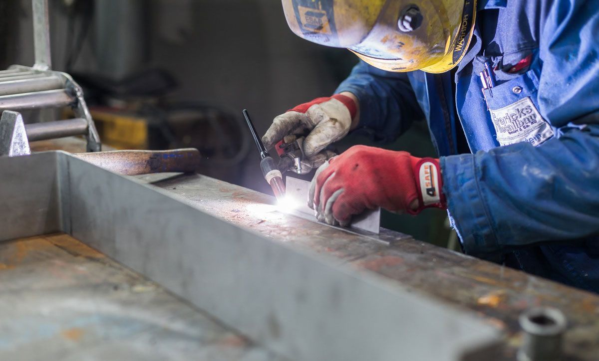 Ein Mann schweißt in einer Fabrik ein Stück Metall.