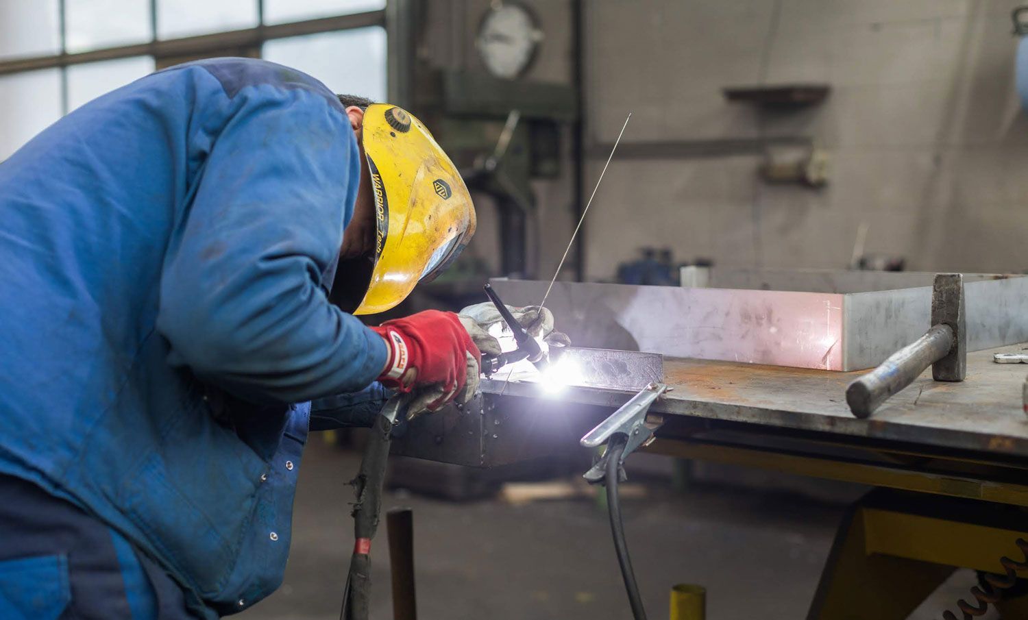 Ein Mann schweißt in einer Fabrik ein Stück Metall.