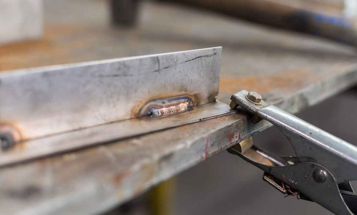 Eine Person schweißt ein Stück Metall mit einer Zange.