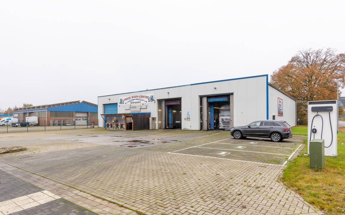 Vor einem großen weißen Gebäude parkt ein Auto.