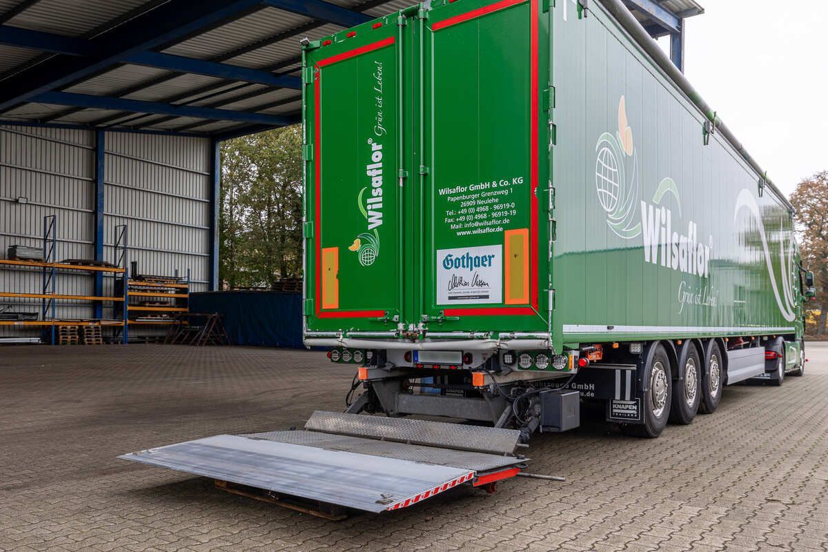 Ein grün-weißer Sattelschlepper steht in einer Lagerhalle.