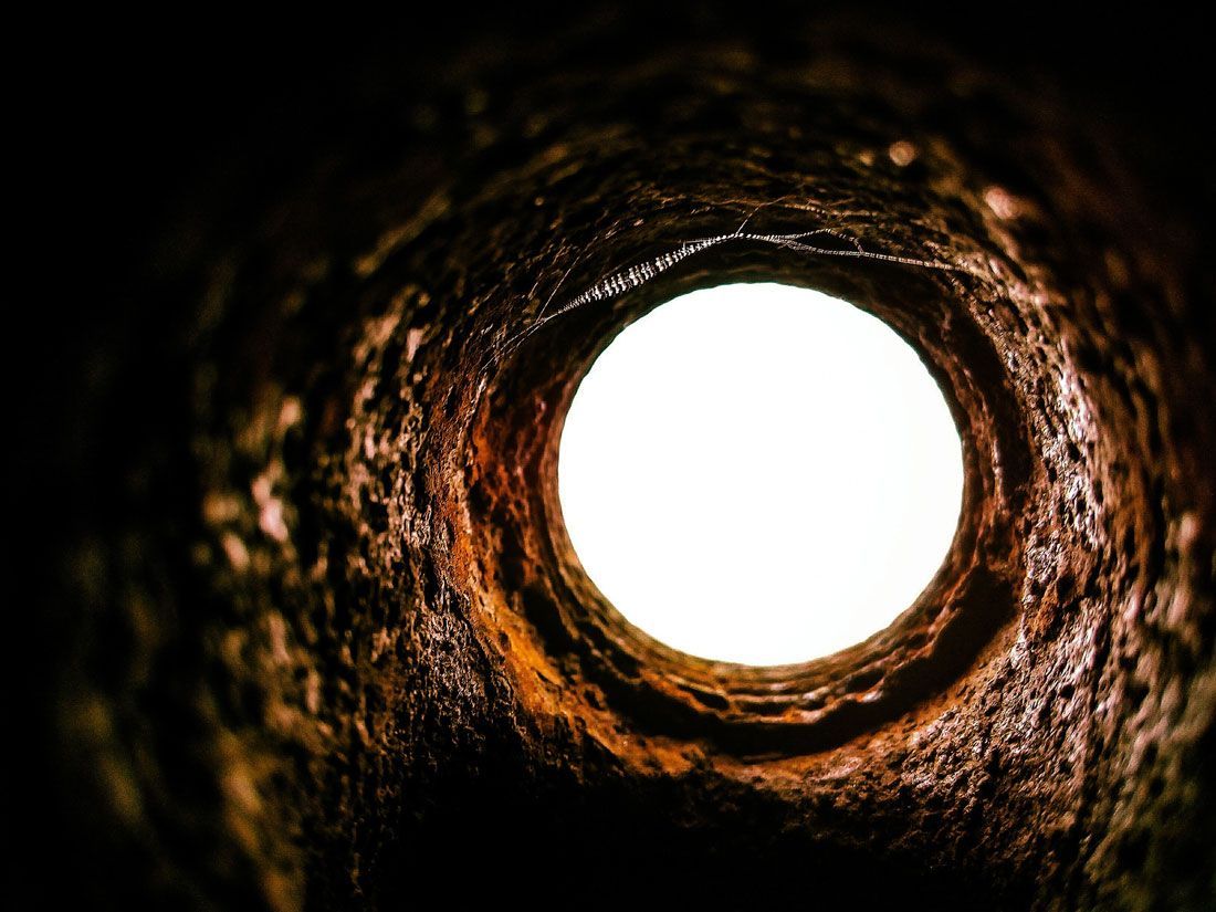 Vue depuis l'intérieur d'un tuyau rouillé vers une ouverture circulaire d'un blanc éclatant