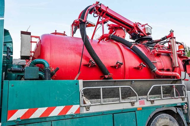 Camion-citerne rouge avec tuyaux et machines montés sur le dessus, vu de profil.