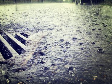 L'eau de pluie déferle sur une rue inondée, près d'une bouche d'égout.