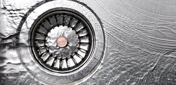 Bonde d'évier en acier inoxydable avec crépine circulaire et eau ondulée autour.