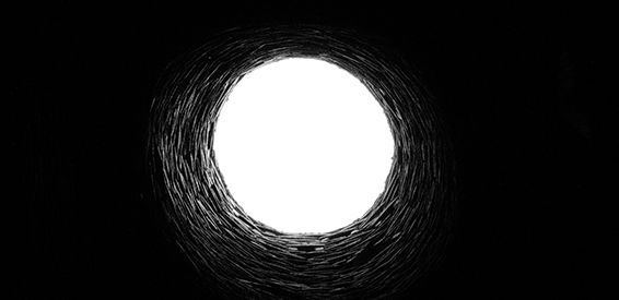 Un cercle blanc brillant sur fond noir, entouré d'anneaux sombres irréguliers et esquissés.