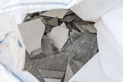 Des éclats de carreaux gris cassés dans un sac blanc.