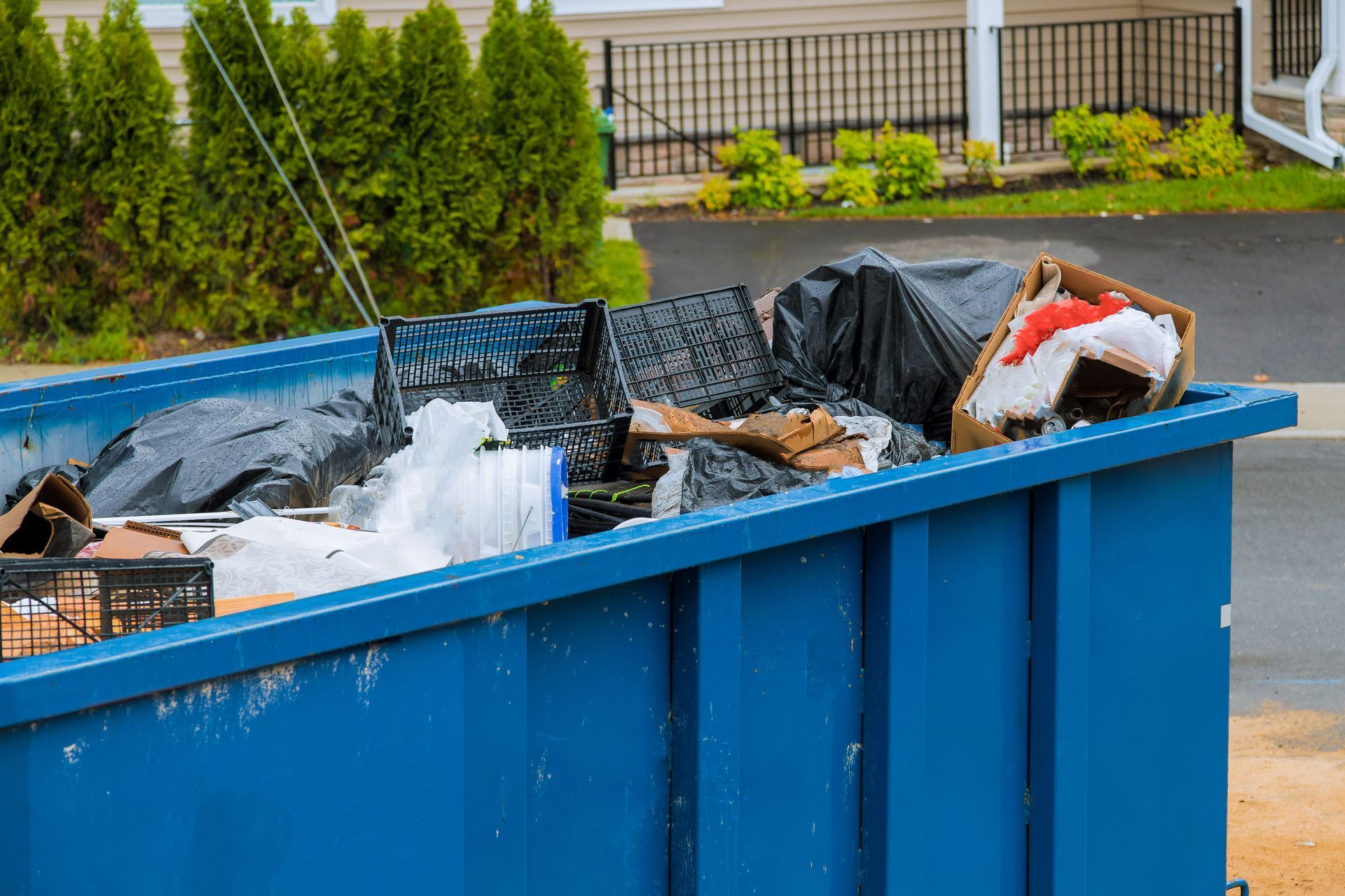 Un conteneur à déchets bleu de chantier, rempli d'ordures et de débris.