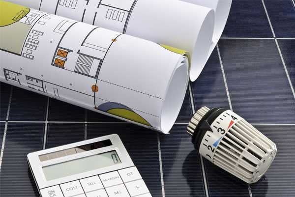 Baupläne, Taschenrechner und Thermostat auf einem Solarpanel.