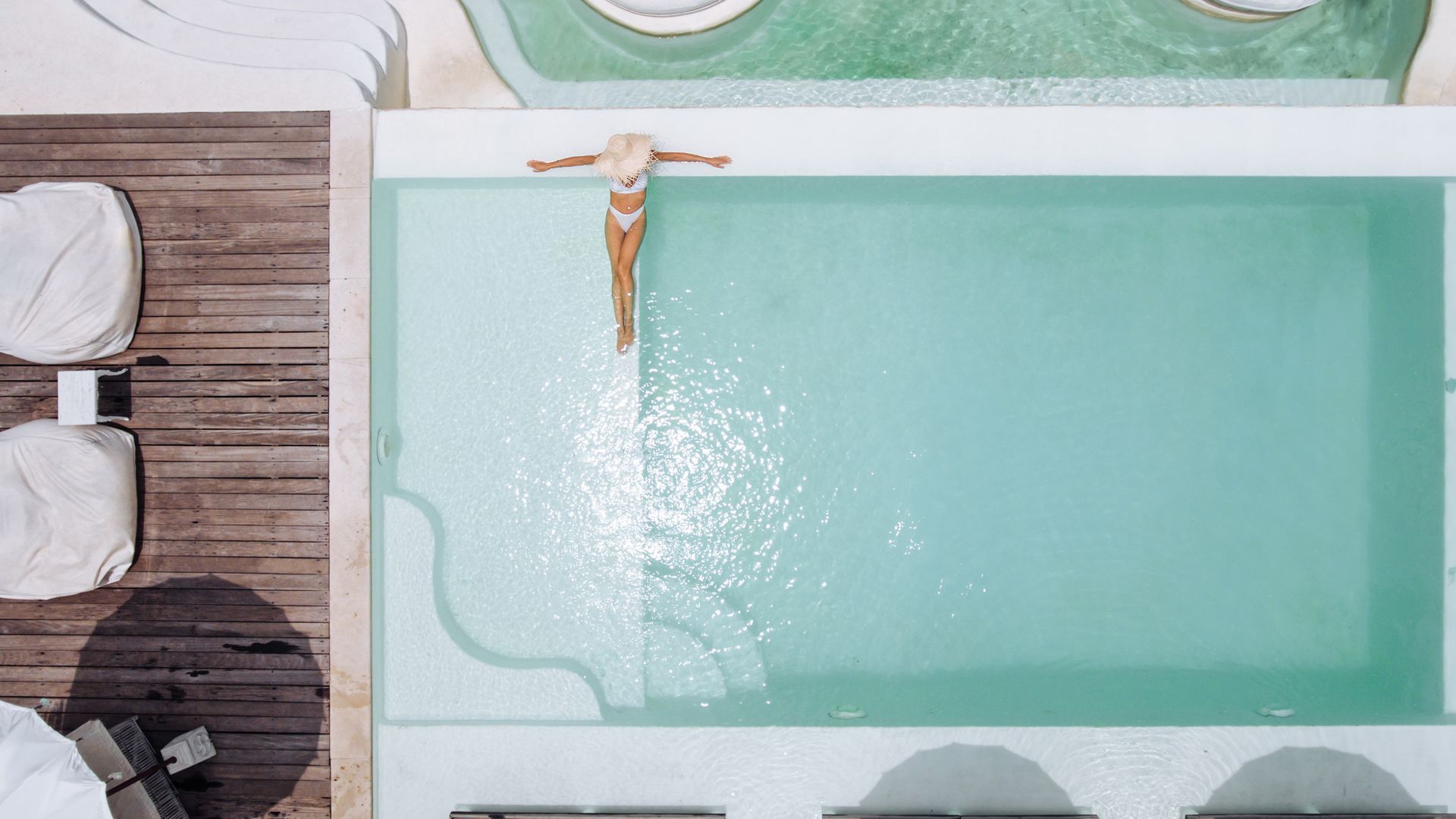 Una vista aérea de una mujer flotando en una piscina.