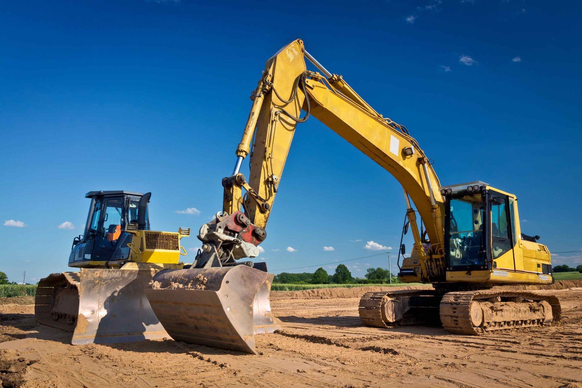 Dos excavadoras amarillas están trabajando en un sitio de construcción.