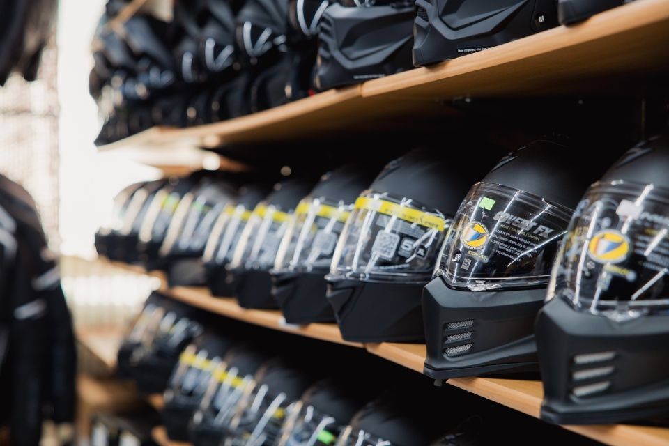 Reihenweise schwarze Helme in den Regalen des Ladens, aufgereiht mit gelben Preisschildern.