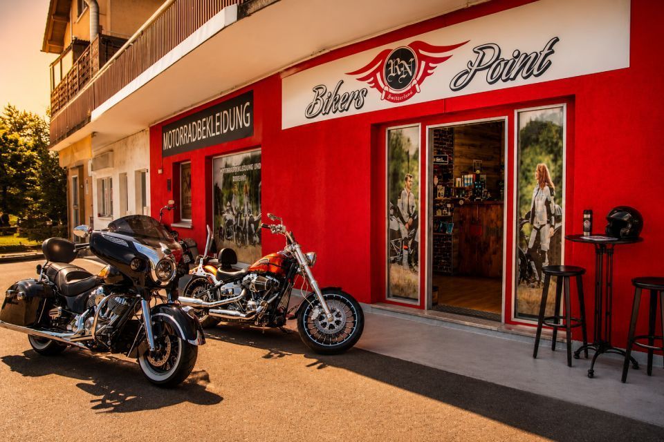 Ein rotes Motorrad parkt vor einem leuchtend roten Ladenlokal mit Glastüren und -fenstern.
