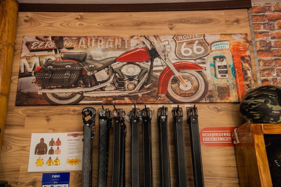 Vintage-Motorrad-Wandbild mit Route-66-Schild über hängenden schwarzen Gurten in einem rustikalen Interieur