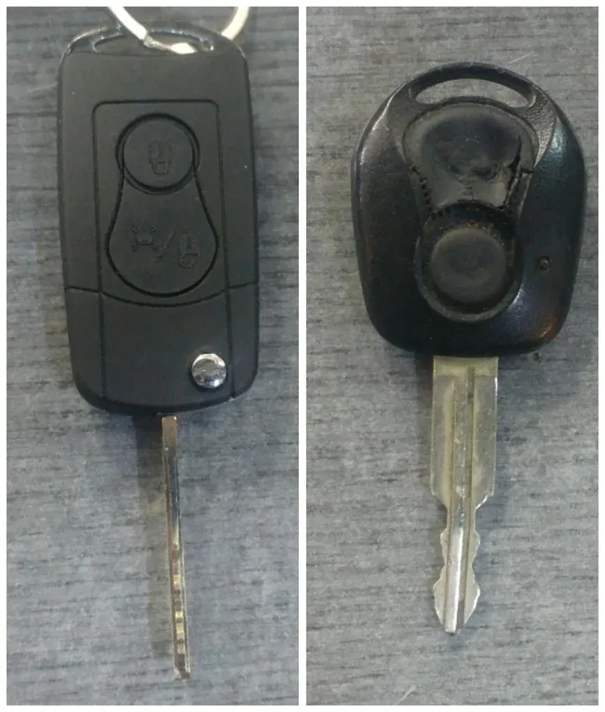 Llavero negro para coche y llave metálica mostrados por delante y por detrás sobre una superficie gris.