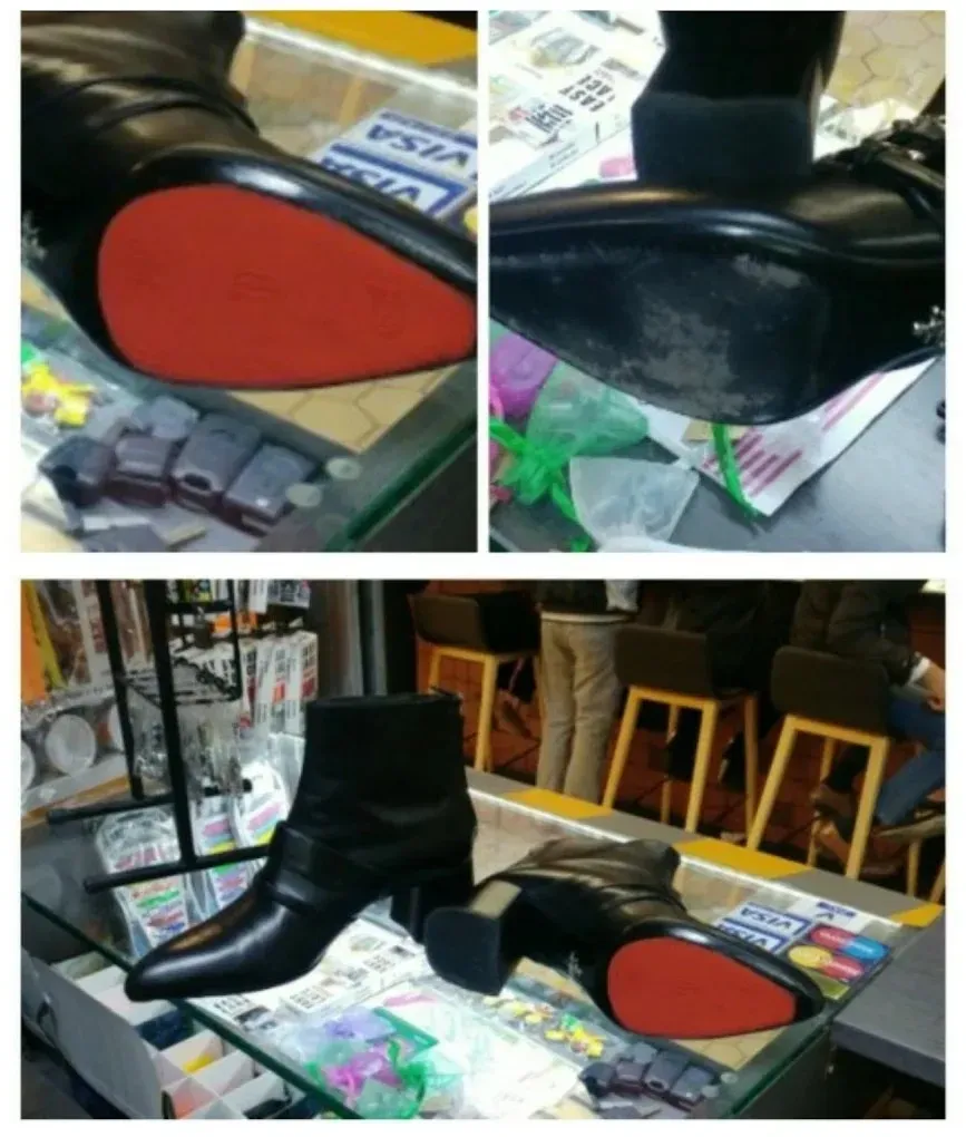 Botines negros con suela roja expuestos sobre una mesa desordenada.