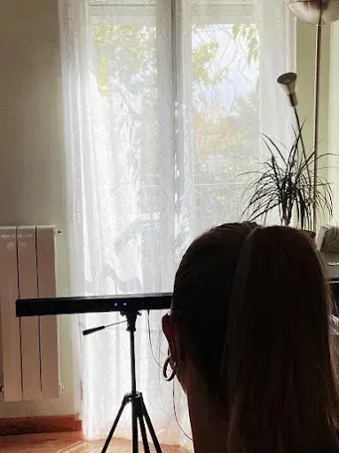 Persona sentada junto a una ventana, cerca de un instrumento montado sobre un trípode