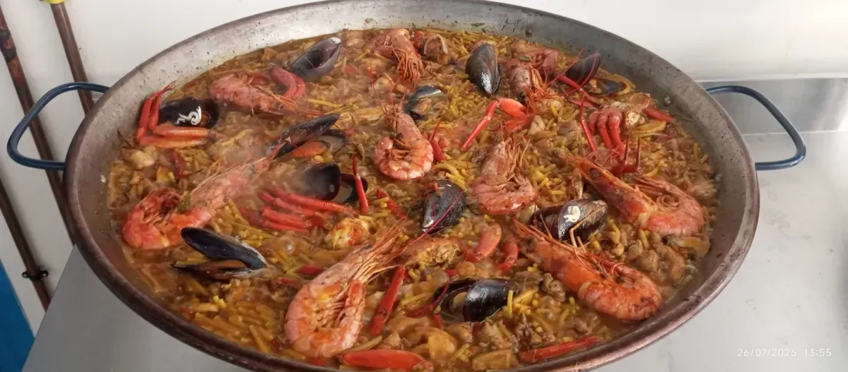 Gran paella de mariscos con camarones, mejillones y arroz en una estufa.