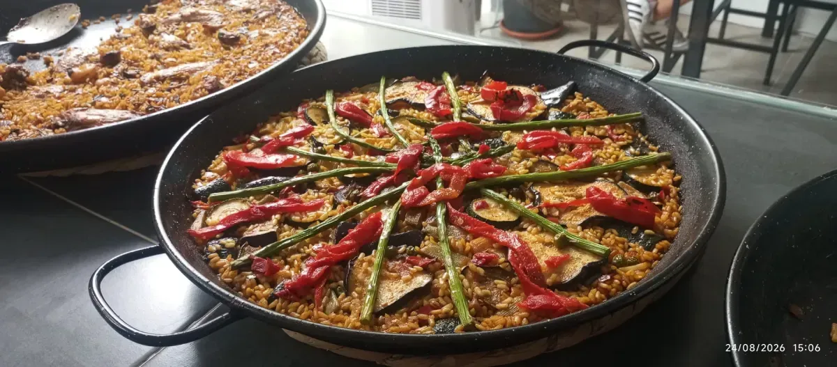 Grandes sartenes de arroz amarillo con mariscos en una mesa de buffet.