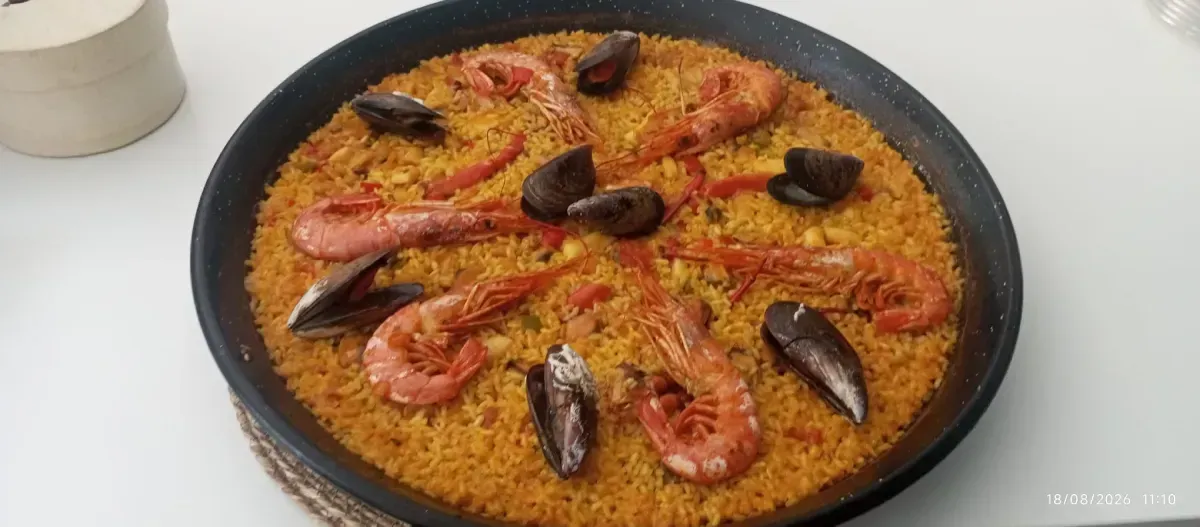 Gran paella de mariscos con camarones, mejillones y arroz en una estufa.