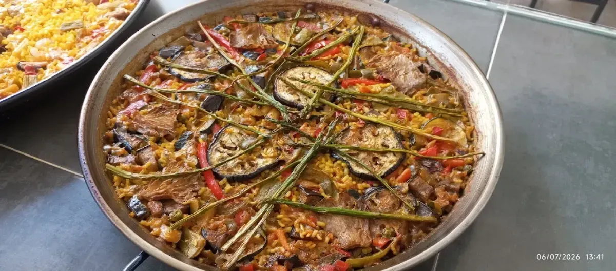 Plato redondo de arroz horneado cubierto con hierbas, rodajas de limón y pescado sobre una mesa.