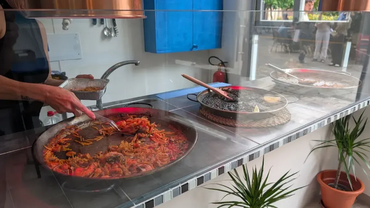 Puesto de comida callejera con un vendedor que sirve una gran olla de estofado rojo junto a platos cubiertos