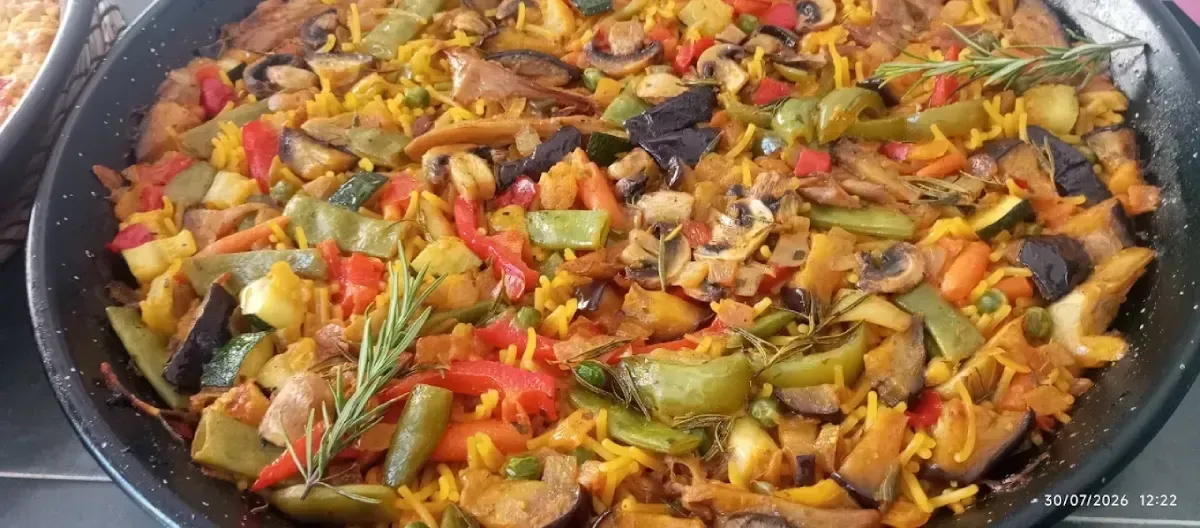 Verduras coloridas salteadas con pimientos y cebollas cocinándose a fuego lento en una sartén grande.