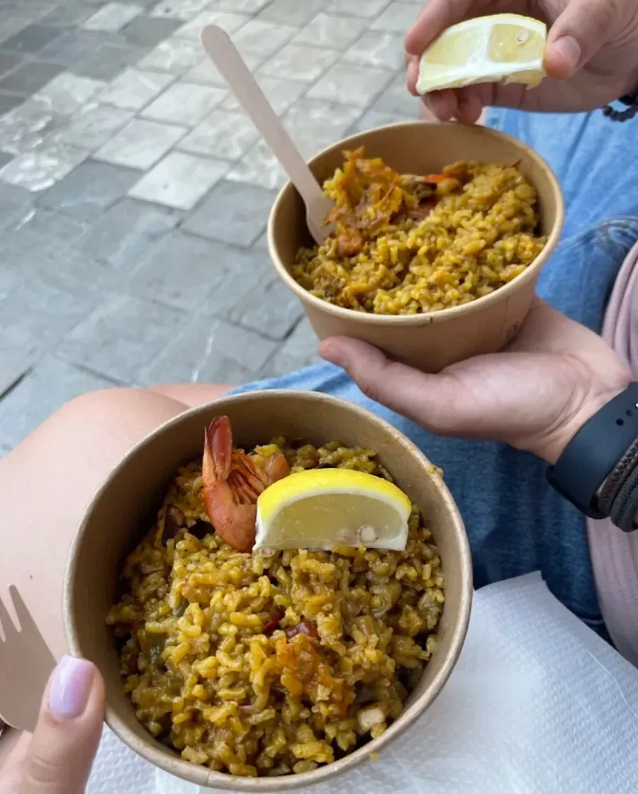 Dos cuencos de arroz amarillo con gambas y rodajas de limón servidos al aire libre.